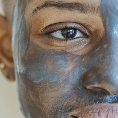 Crop African American female taking care of skin with cleansing clay mask